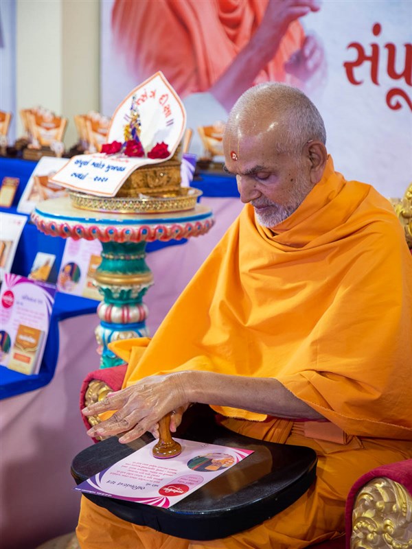 Swamishri applies a stamp of approval on a certificate