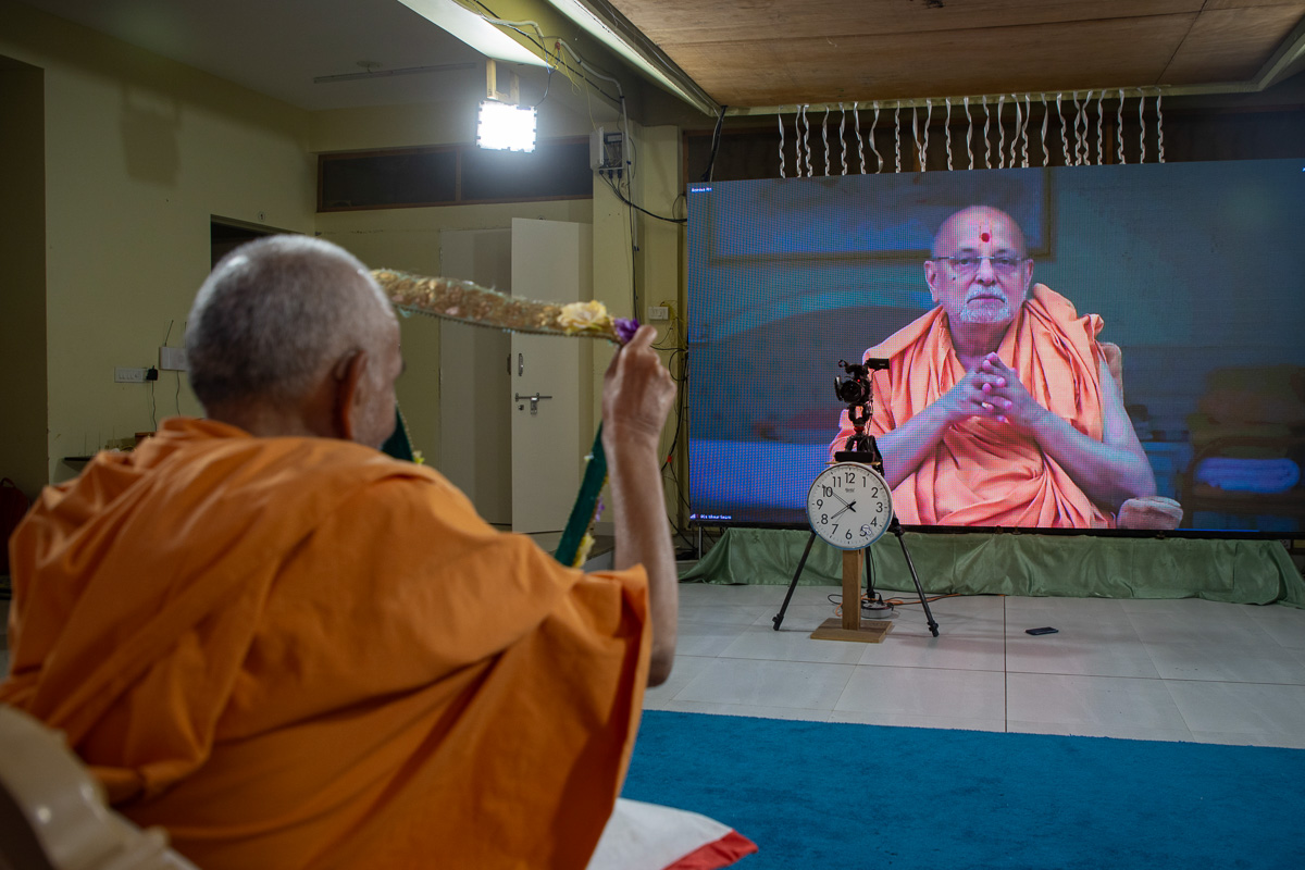 Swamishri honors Pujya Ishwarcharan Swami with a garland