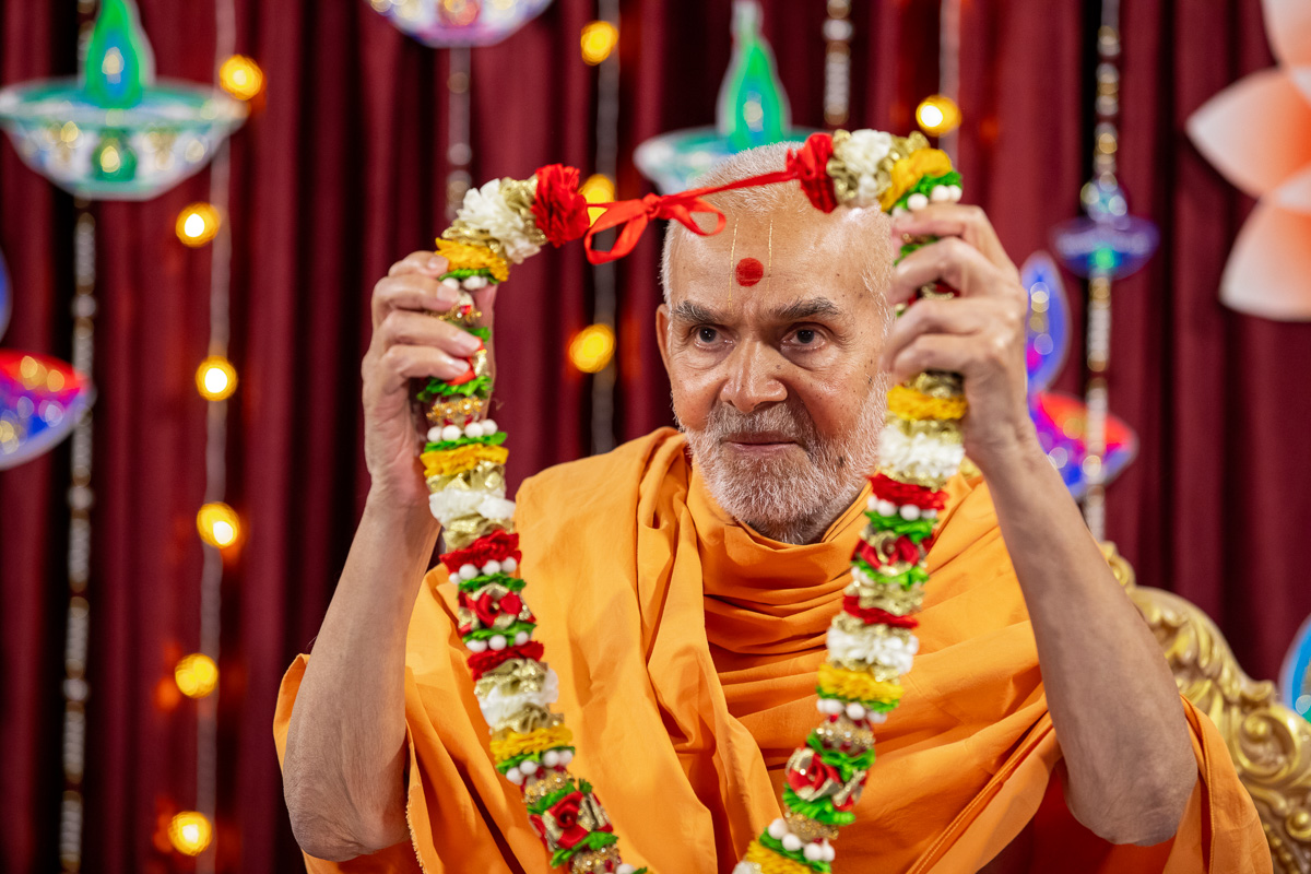 Swamishri honors Pujya Bhaktipriya Swami (Kothari Swami) with a garland