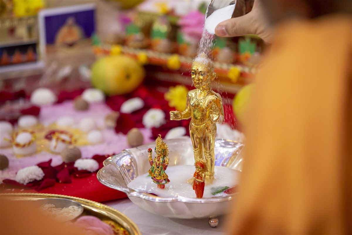 Swamis bathed the murti with finely granulated sugar