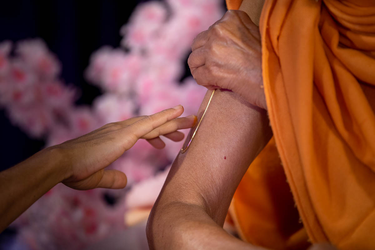 Swamishri applies a tilak on his upper arm during his daily puja