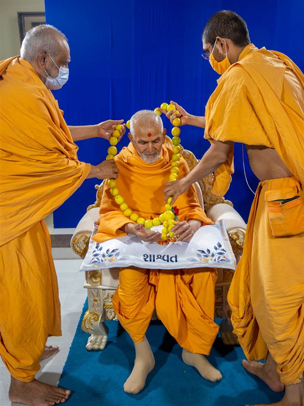 Sadhus honor Swamishri with a lemon garland