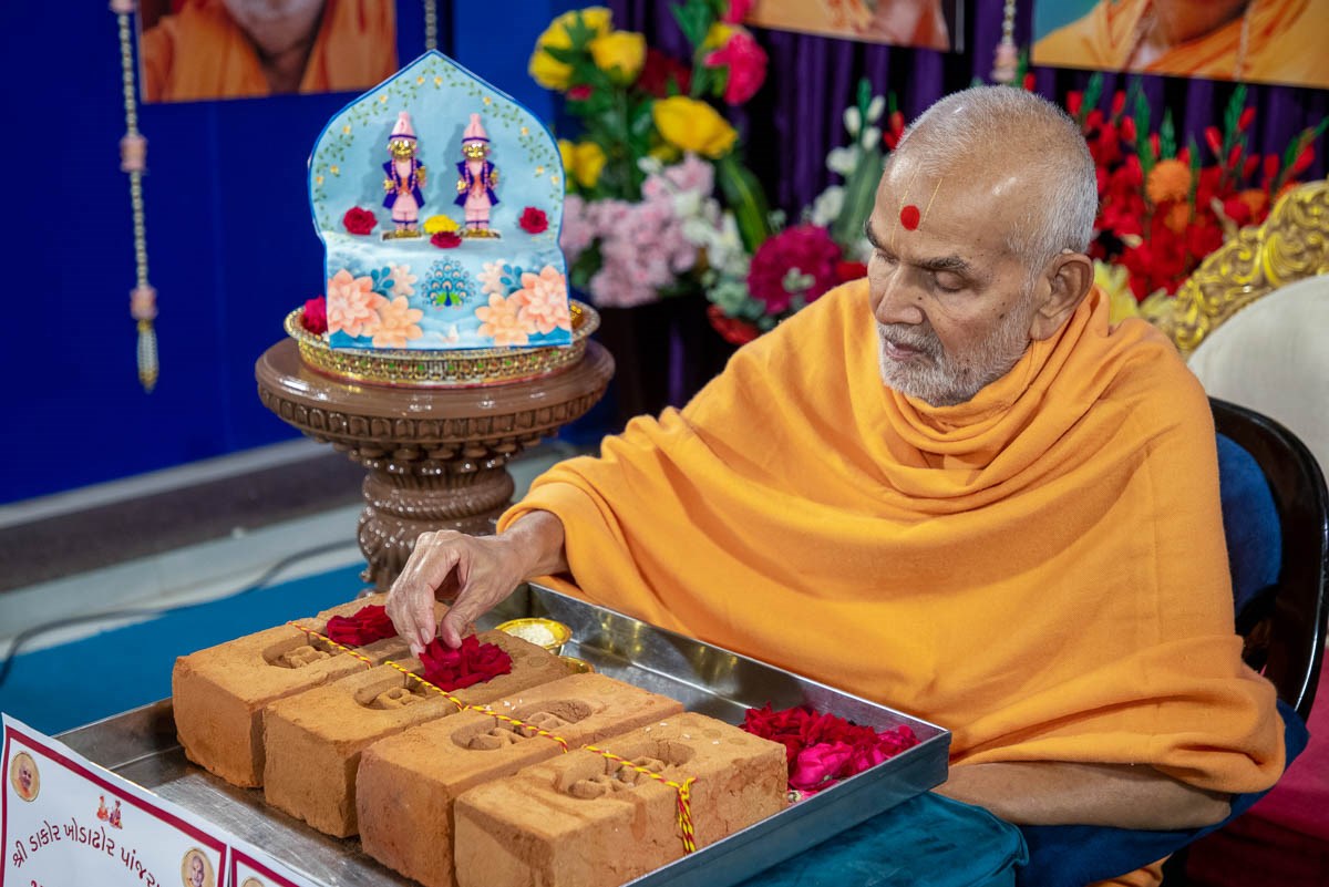 Swamishri sanctifies the bricks with flowers