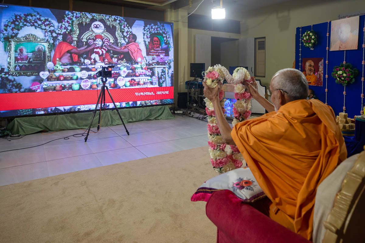 Swamishri honors Brahmaswarup Pramukh Swami Maharaj's murti in Chansad with a garland via video conference