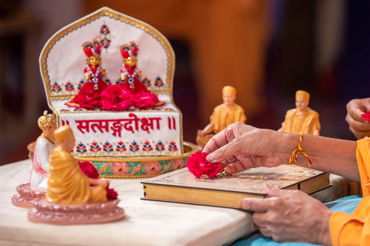 Swamishri offers a flower on the Satsang Diksha