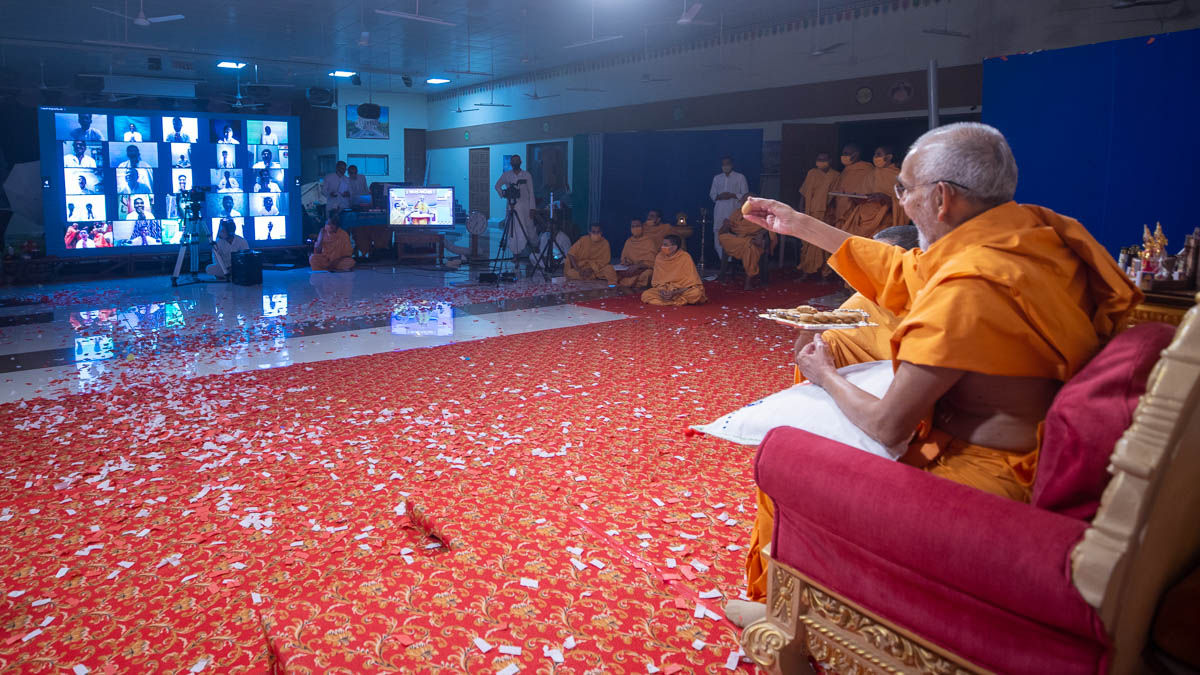 Swamishri gives prasad to the youths via video conference
