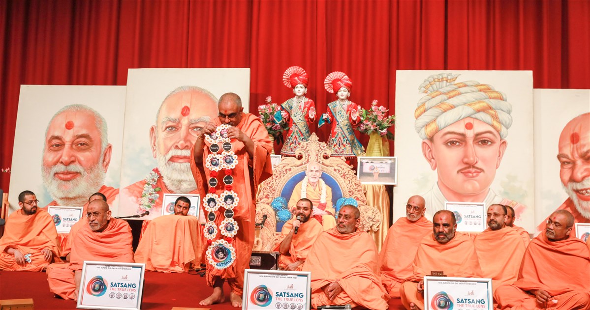 Yogvivekdas Swami in London offered to Mahant Swami Maharaj a decorative garland crafted by the yuvatis of UK & Europe