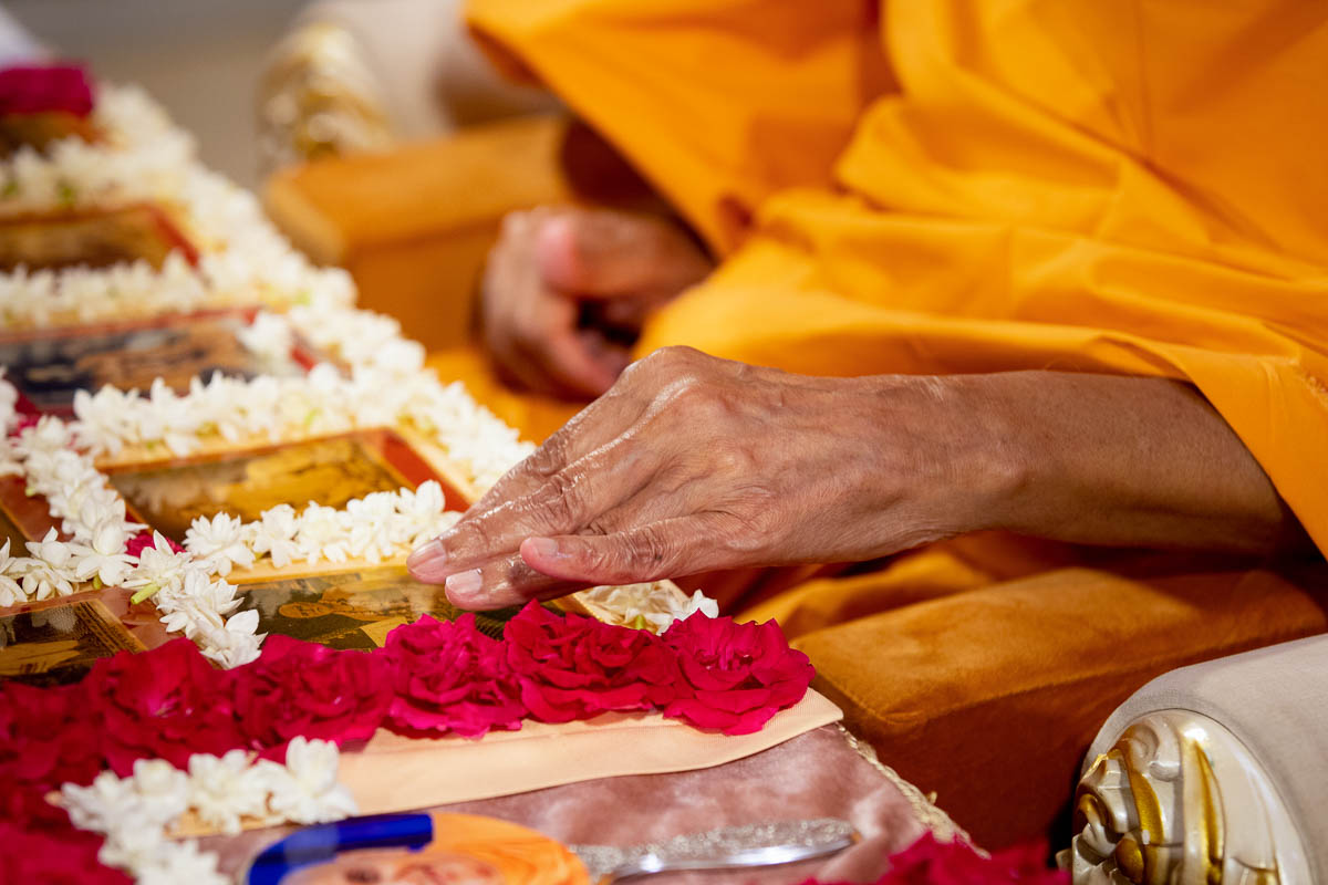 Swamishri adjusts a murti before beginning his daily puja