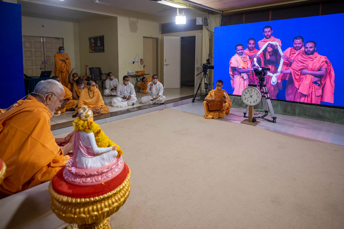 Sadhus honor Swamishri with a garland via video conference