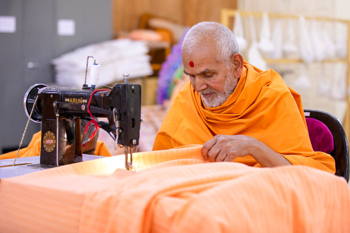 Swamishri operates a sewing machine