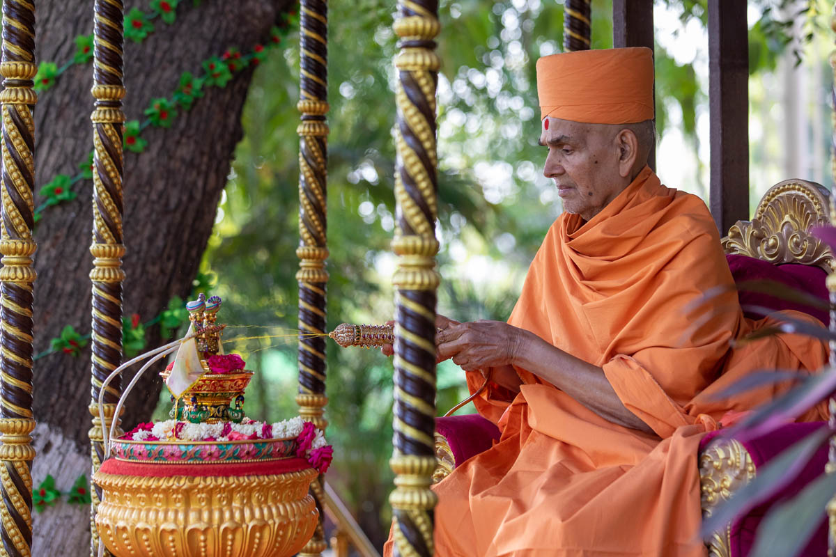 Swamishri sprays saffron-scented water on Shri Harikrishna Maharaj and Shri Gunatitanand Swami