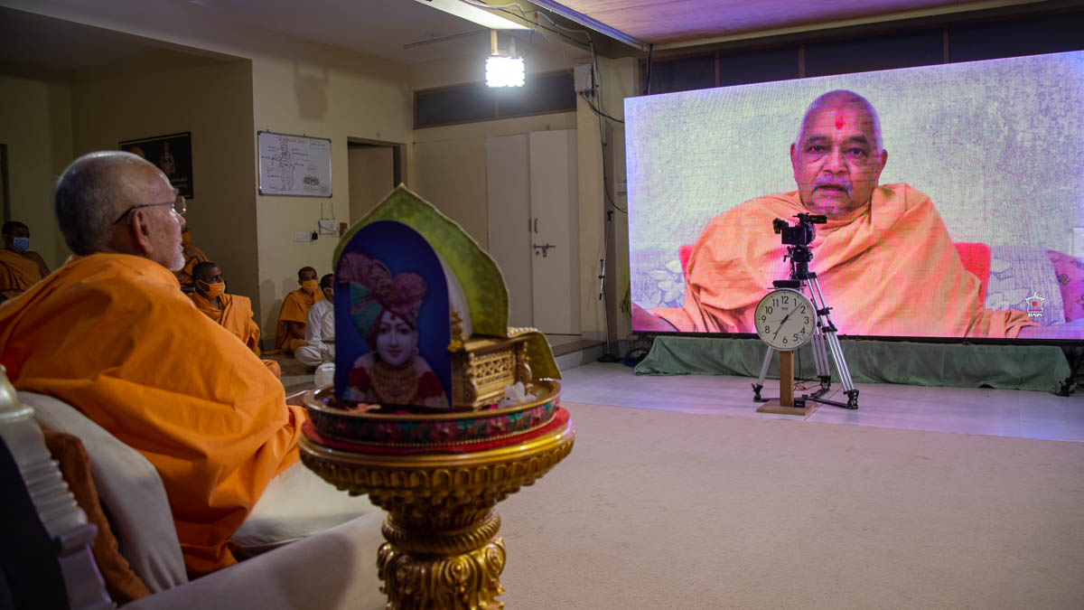 Swamishri watches a video during the assembly