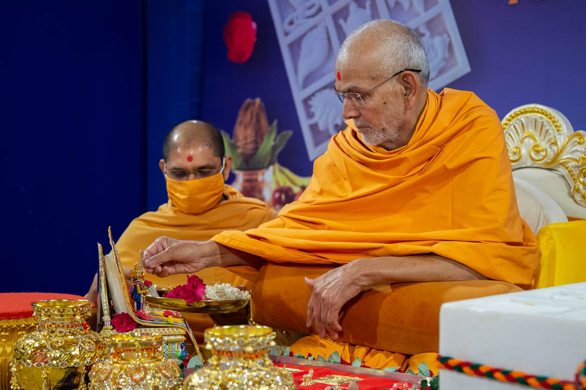 Swamishri performs offers rice grains to Shri Harikrishna Maharaj and Shri Gunatitanand Swami