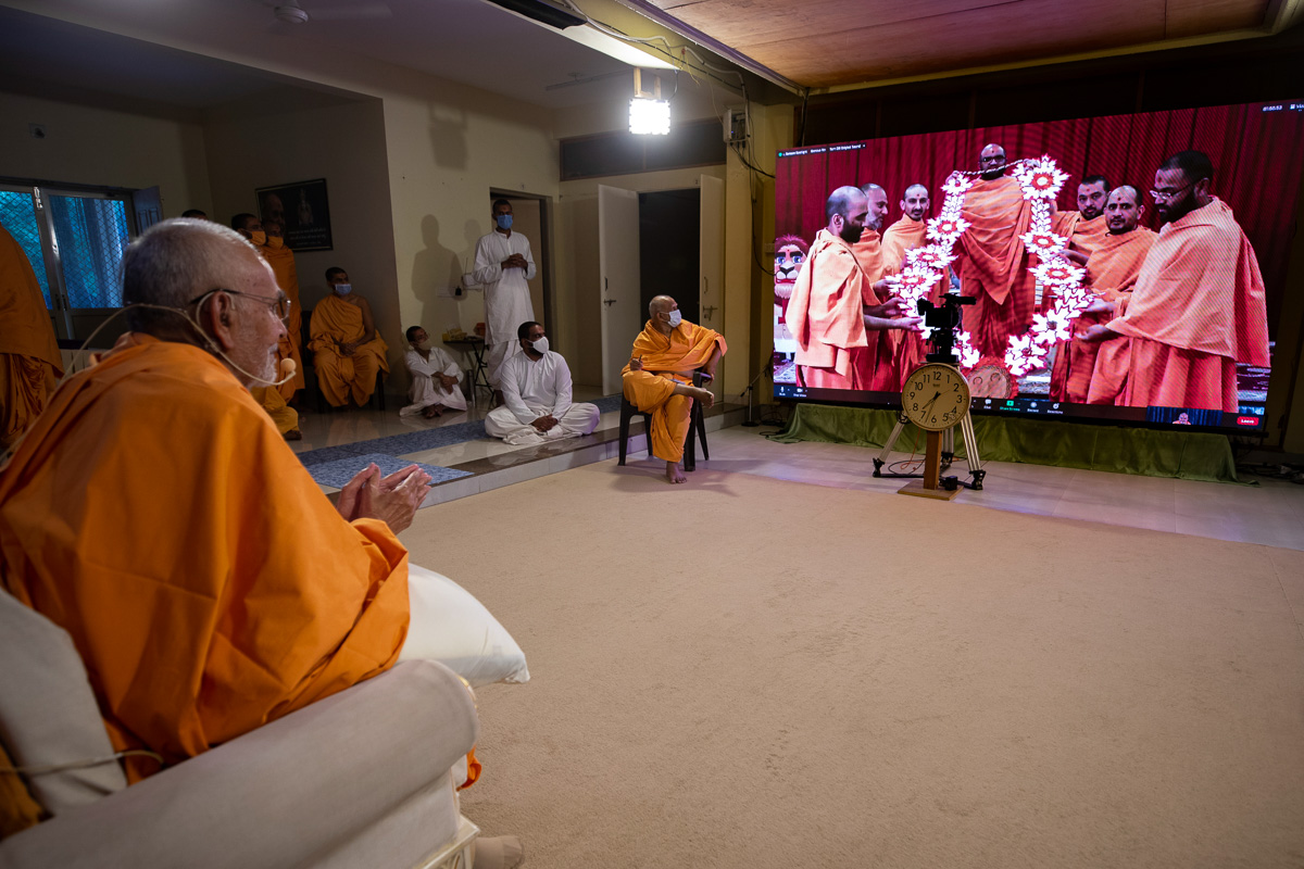 Sadhus honor Swamishri with a garland via video conference from Toronto Mandir