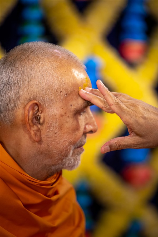 Atmaswarup Swami applies chandan archa on Swamishri's forehead