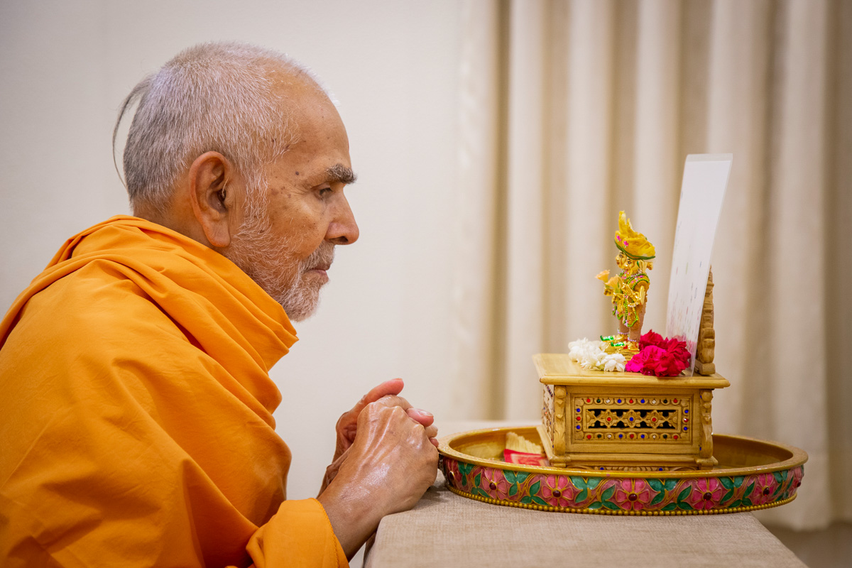 Swamishri engaged in darshan of Shri Harikrishna Maharaj and Shri Gunatitanand Swami adorned in chandan garments