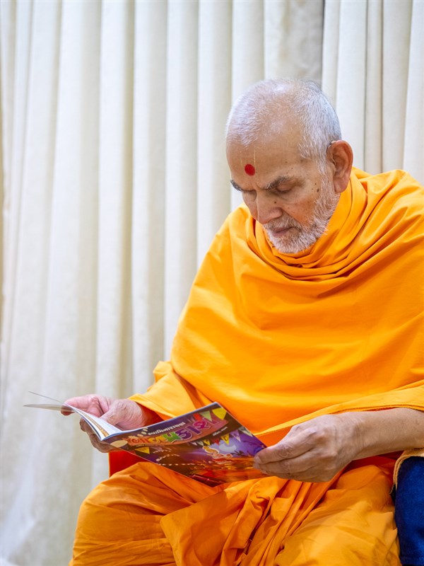Swamishri reads the 'Swaminarayan Bal Prakash'