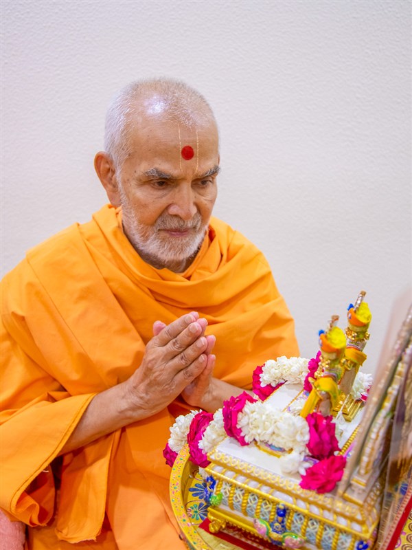 Swamishri engaged in darshan of Shri Harikrishna Maharaj and Shri Gunatitanand Swami adorned in chandan garments