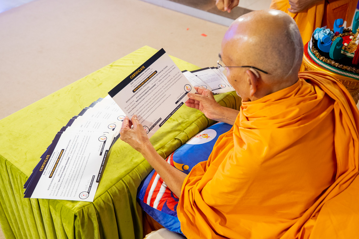 Swamishri observes and sanctifies the certificates to be presented to the youths