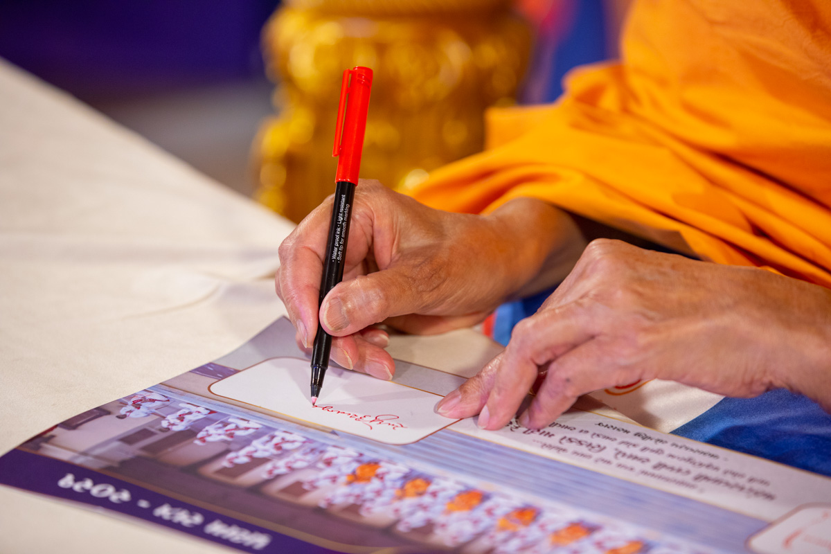 Swamishri signs a photo