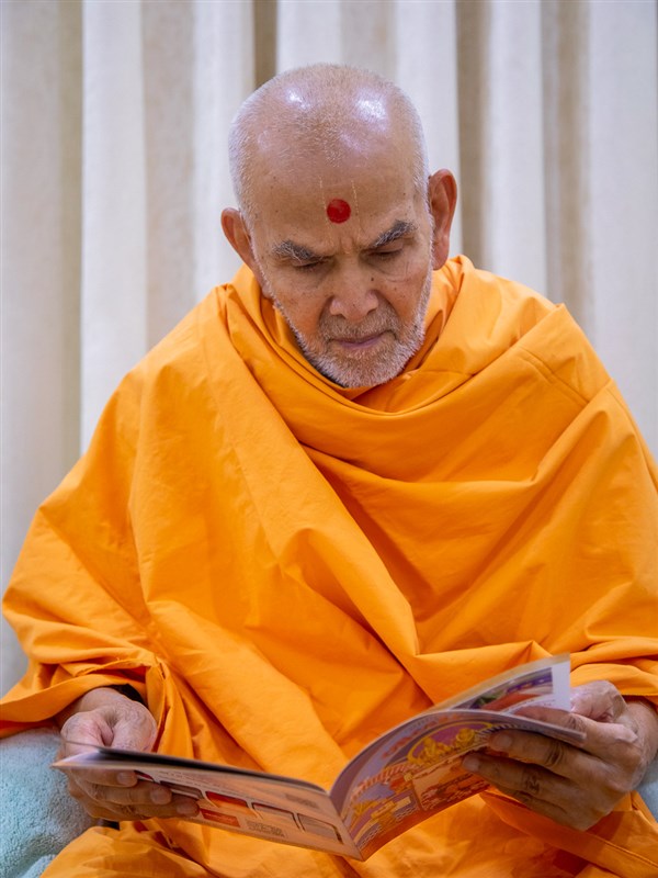 Swamishri reads the 'Swaminarayan Bal Prakash'
