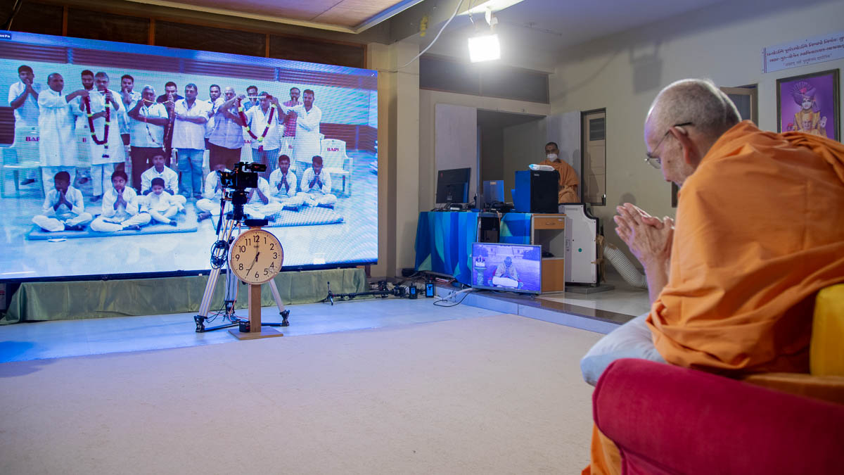 Devotees honor Swamishri with a garland via video conference