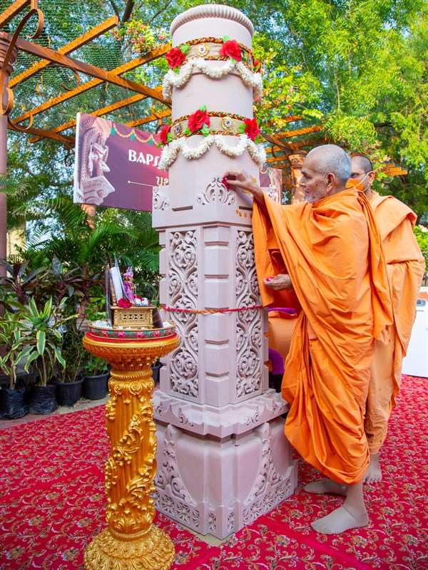 Swamishri puts flowers on the pillar
