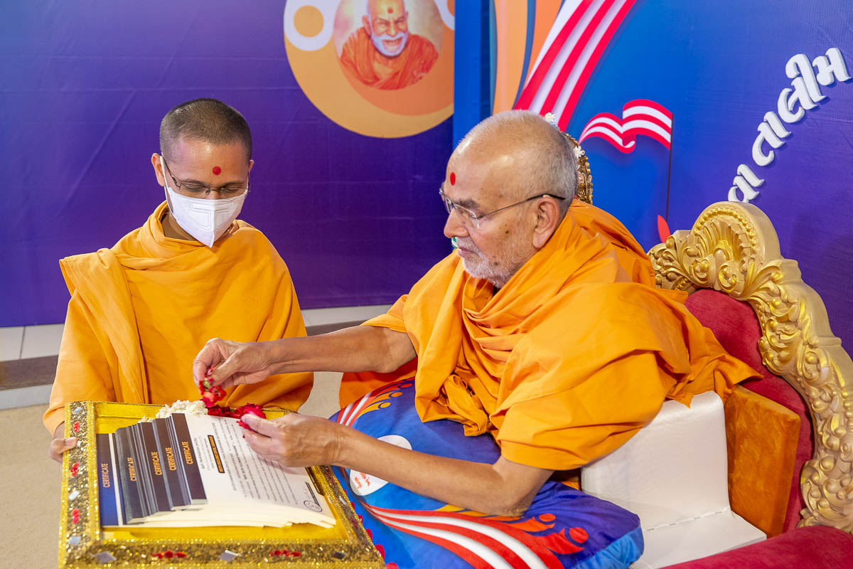 Swamishri sanctifies the certificates to be presented to the youths