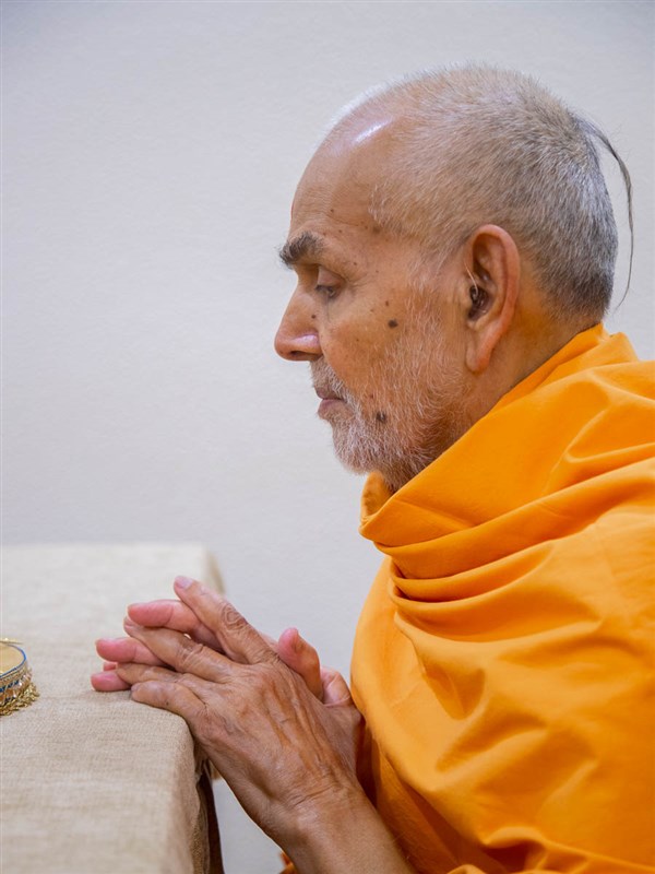 Swamishri engrossed in darshan of Shri Harikrishna Maharaj and Shri Gunatitanand Swami adorned in chandan garments