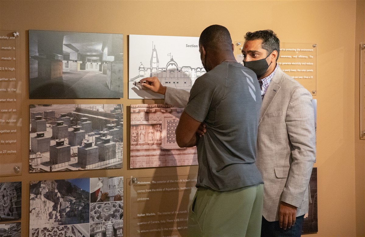A BAPS volunteer guides Jamaican sprinter and Olympian Yohan Blake through the Mandir Exhibition, explaining the construction and history of the Mandir.