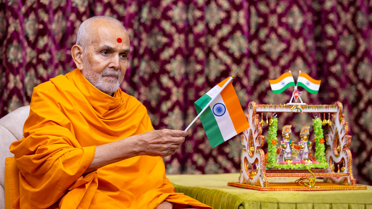 Swamishri waves an Indian flag to commemorate India's Independence Day