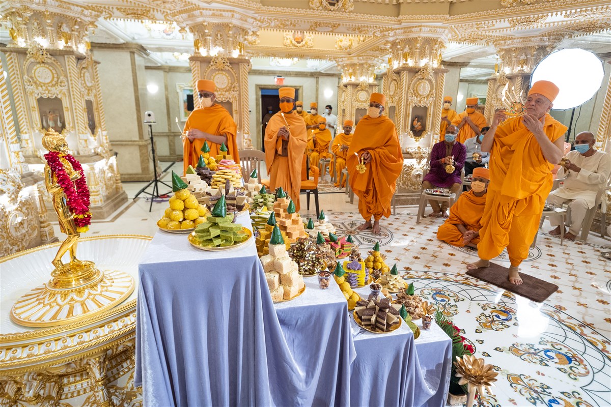 Pujya Ishwarcharan Swami performs arti alongside Swamis and devotees