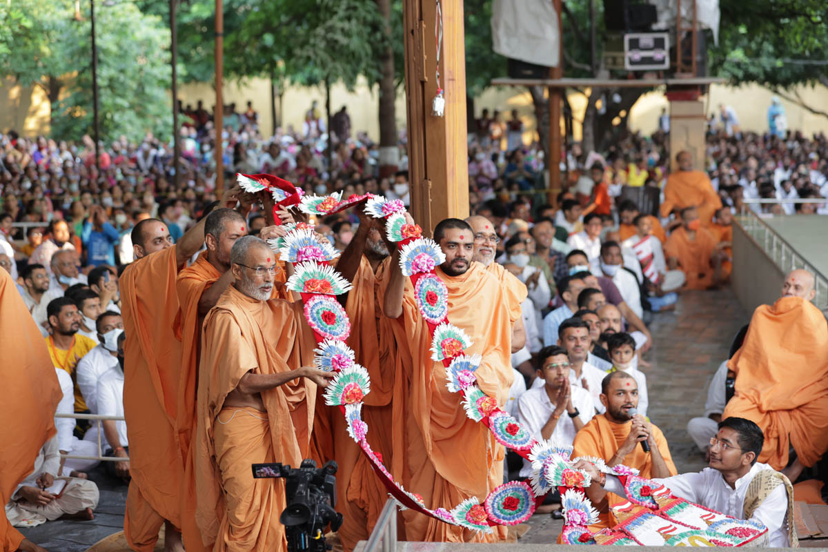 Sadhus from Bhavnagar honor Swamishri with a garland to commemorate the 50th patotsav of the BAPS Lati Bazaar Mandir in Bhavnagar