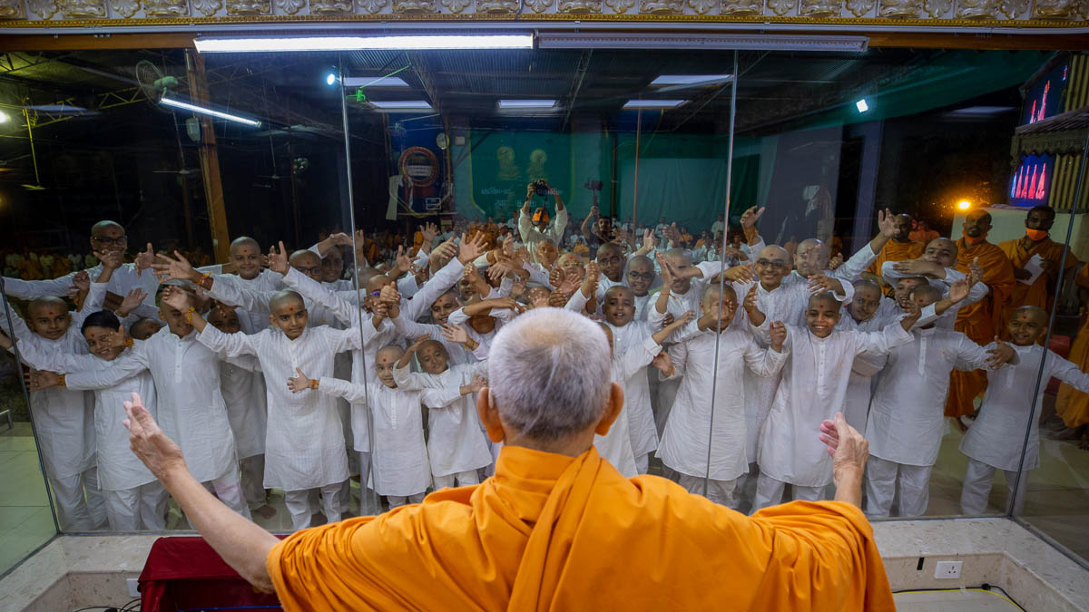 Swamishri gestures to embrace children who have memorized the Siddhant Karika