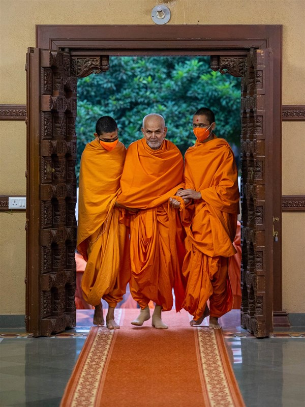 Swamishri returns after darshan for his morning puja