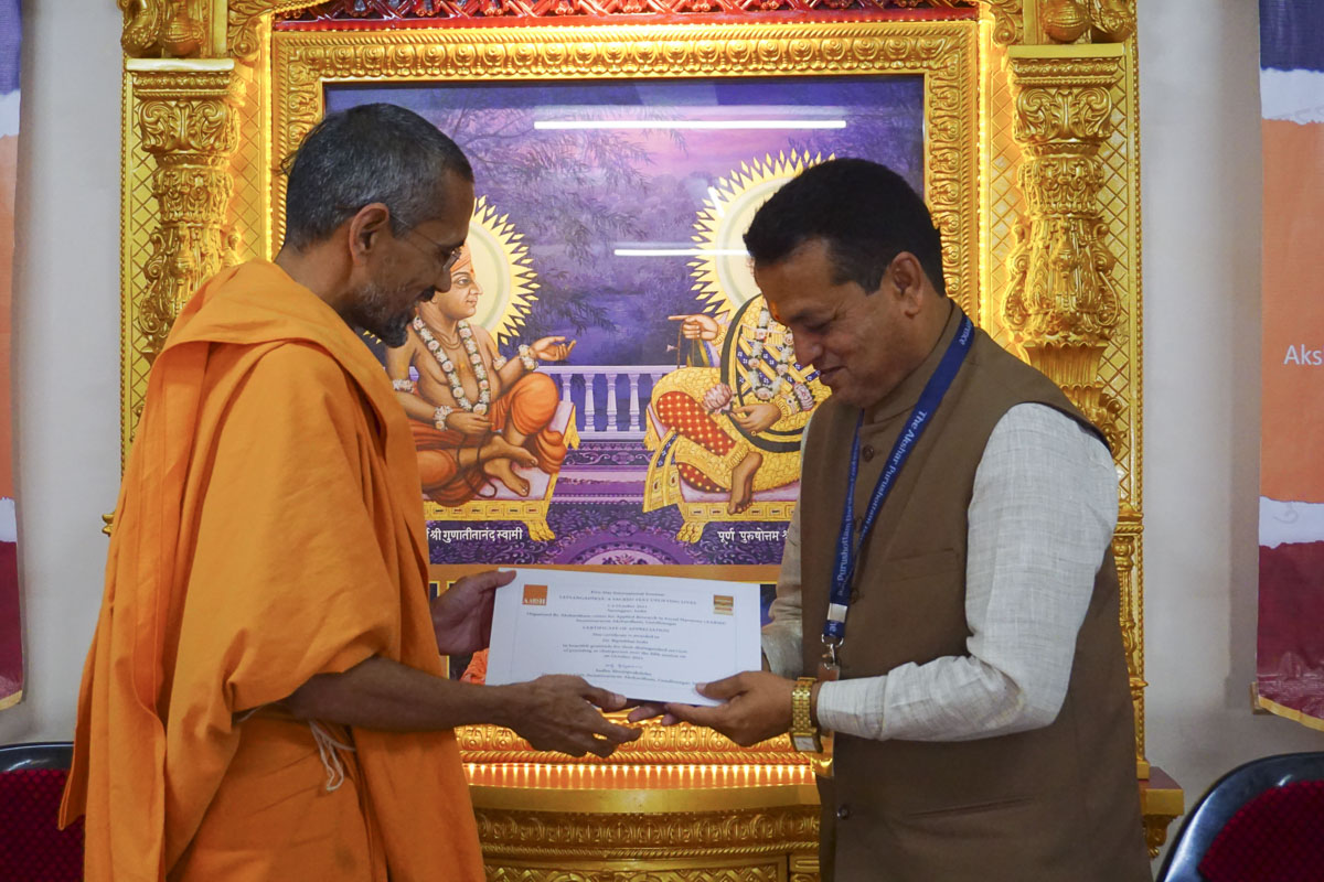 Atmatrupt Swami presents a certificate to a chairperson