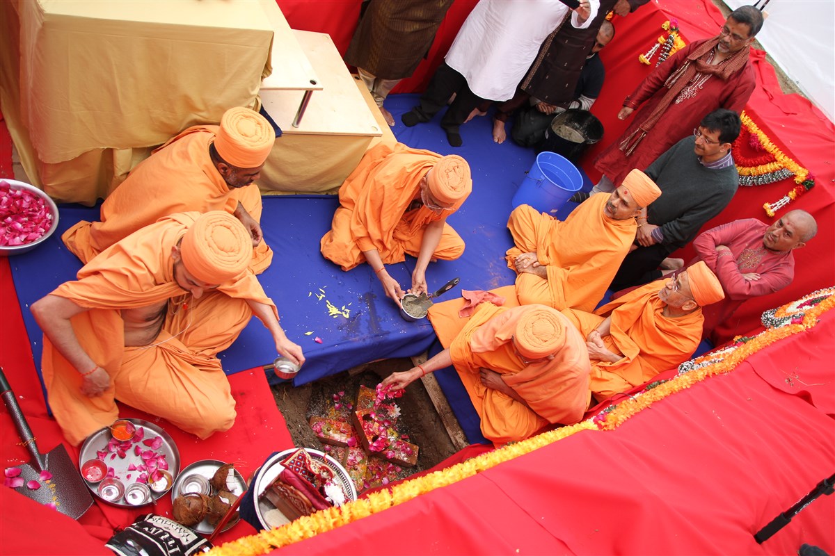 Pujya Kothari Swami places the bricks sanctified by Pramukh Swami Maharaj in the foundations of the new mandir