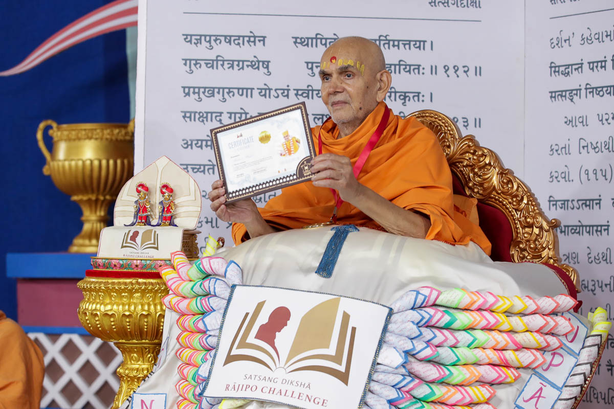 Swamishri displays a certificate