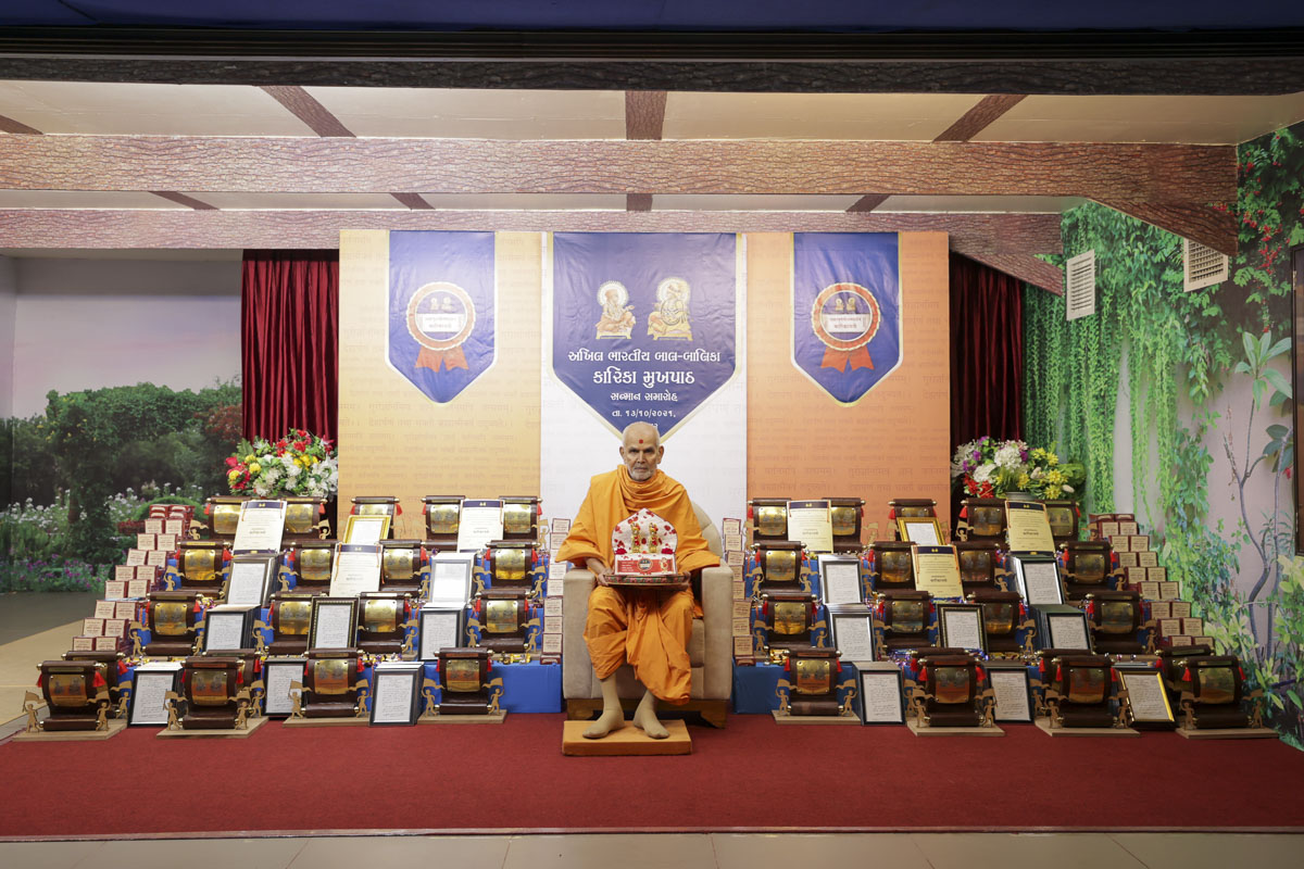 Swamishri sanctifies trophies and certificates to be presented to balaks and balikas who memorized the 565 shlokas of the Swaminarayan Siddhant Karika