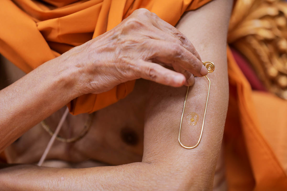 Swamishri applies a tilak on his upper arm