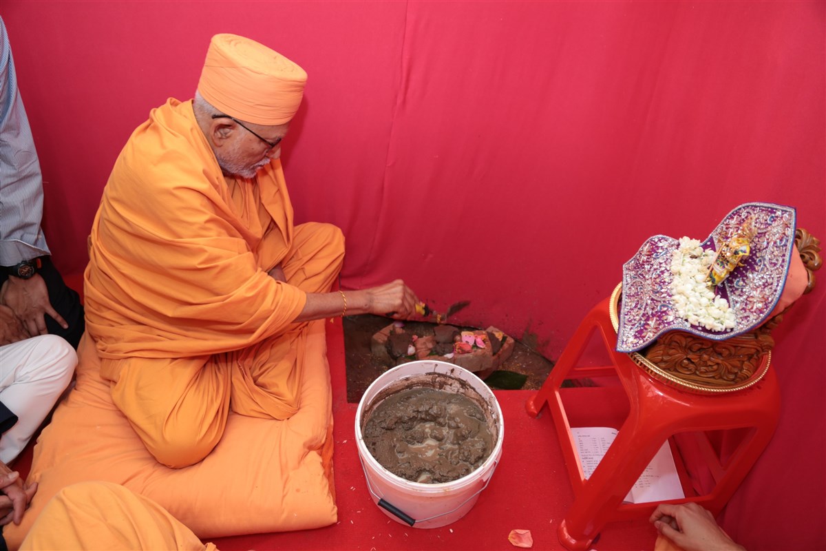 Pujya Kothari Swami places the bricks sanctified by Pramukh Swami Maharaj in the foundations of the new mandir