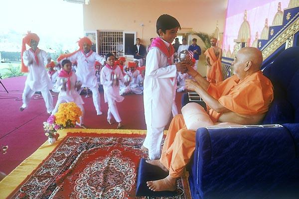  After his puja Swamishri participates by playing 'ghughra' while devotees of Badalpur sing bhajans