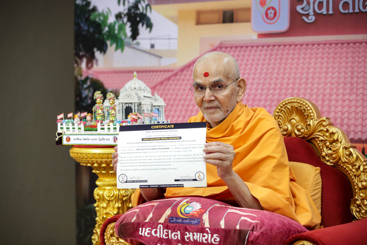 Swamishri displays a certificate for the youths