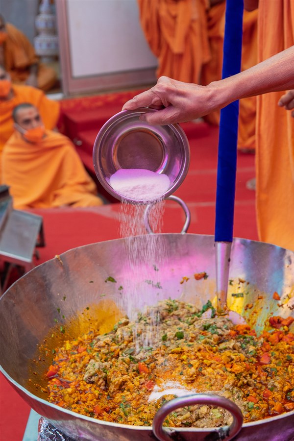 Swamishri adds ingredients to the shak mixture
