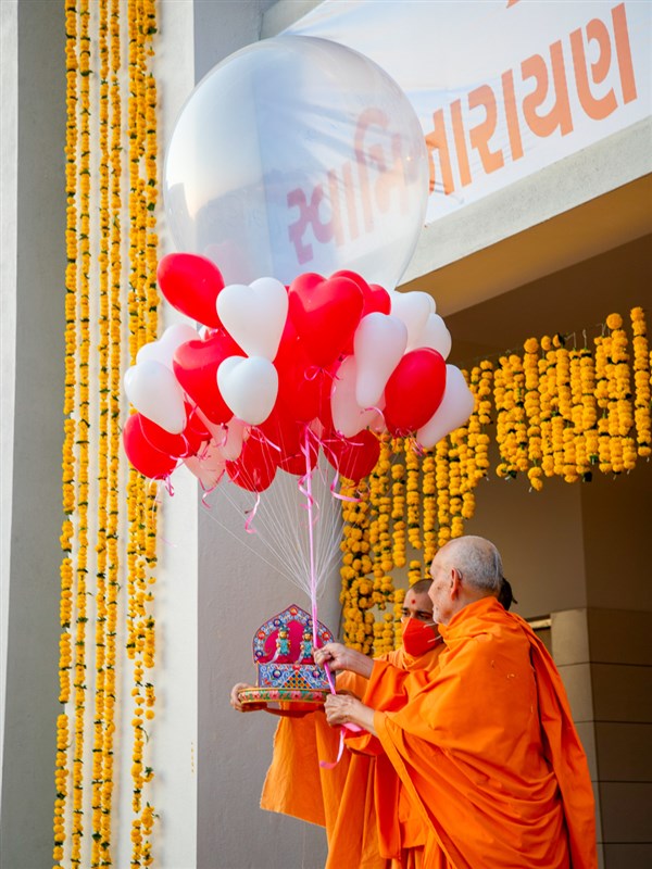 Swamishri offers balloons to Shri Harikrishna Maharaj and Shri Gunatitanand Swami to sanctify