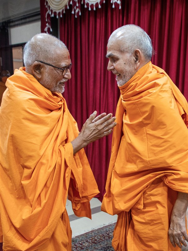 Pujya Kothari Swami greets Swamishri with folded hands