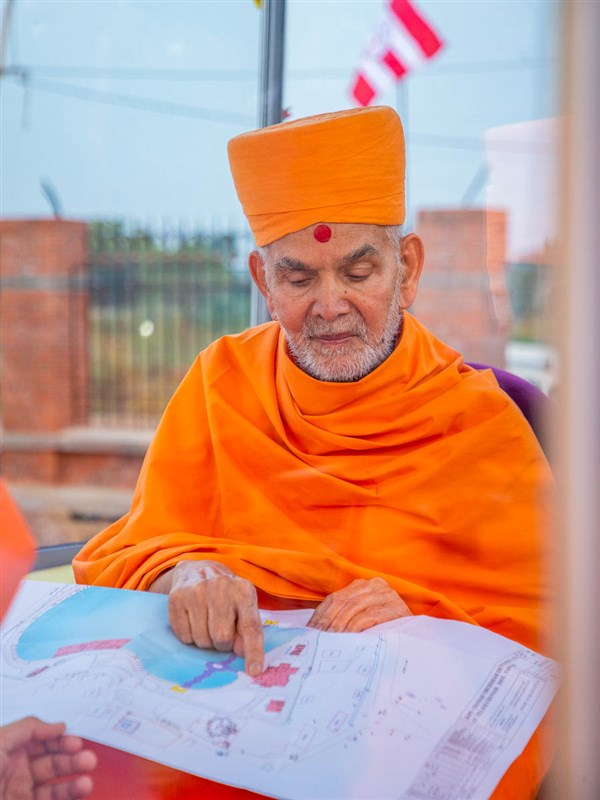 Swamishri observes the map