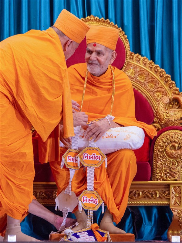 Pujya Ishwarcharan Swami honors Swamishri with a garland