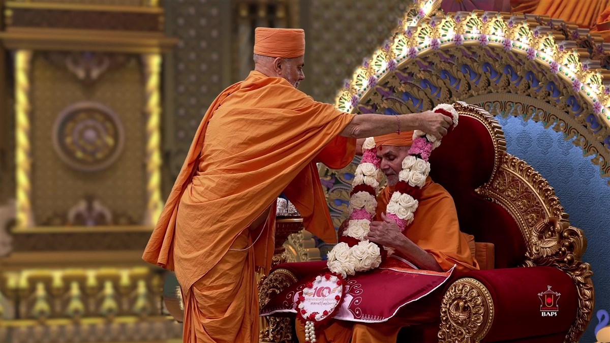 Pujya Viveksagar Swami honors Swamishri with a garland