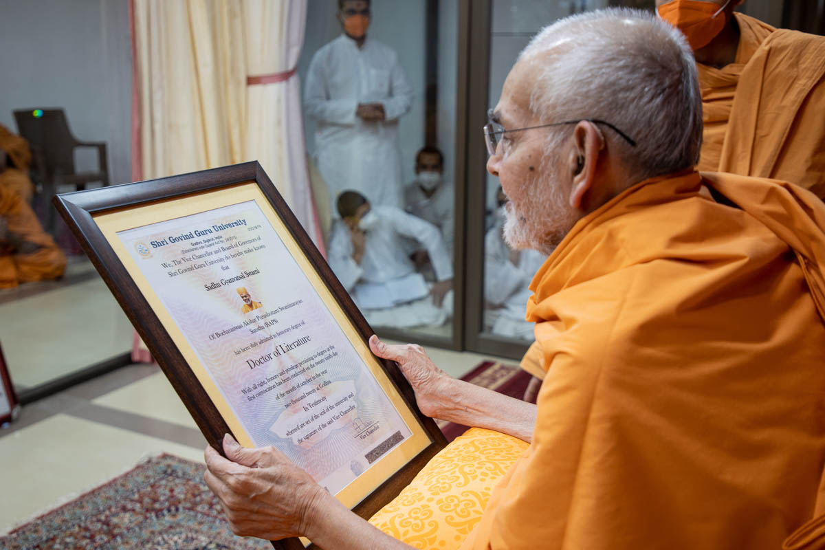 Swamishri sanctifies a certificate awarded to Gnanvatsal Swami